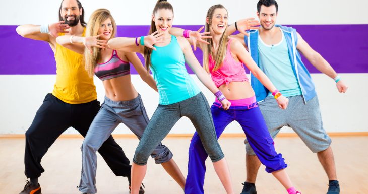 Group of men and women dancing zumba fitness choreography in dance school